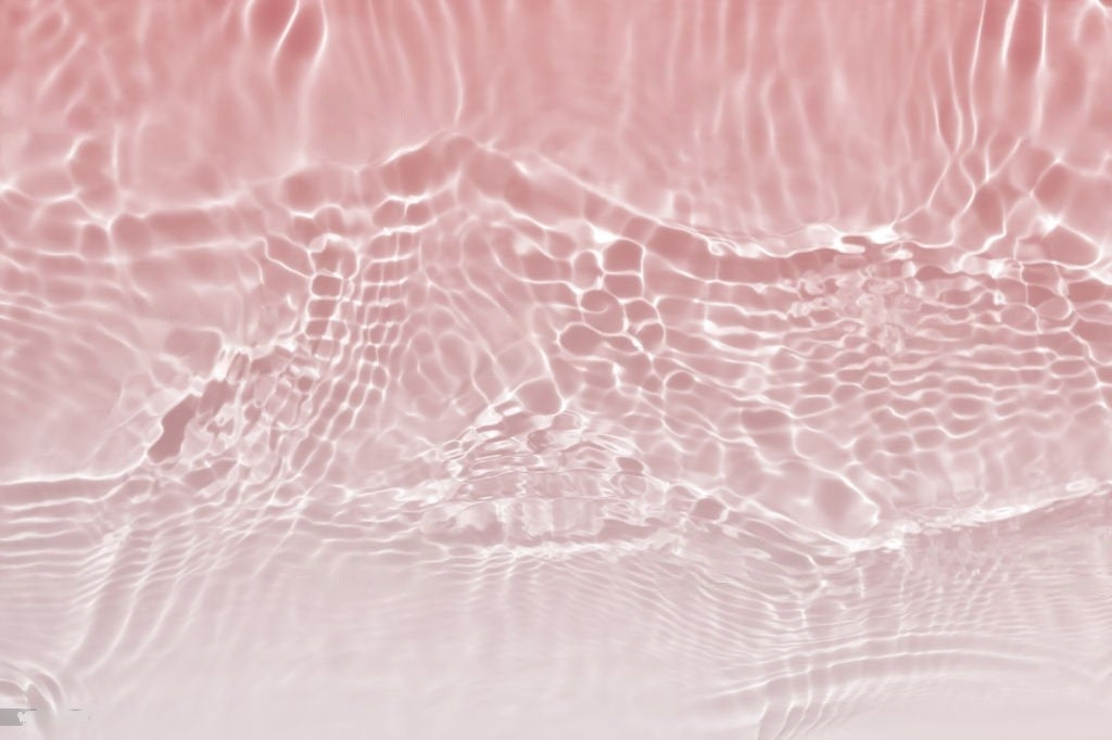 Reflets de l'eau grâce au soleil sur du sable rosé légèrement en mouvement